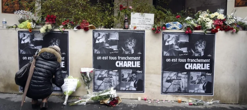 Μια γυναίκα βάζει λουλούδια κοντά στα γραφεία της γαλλικής σατιρικής εφημερίδας Charlie Hebdo στις 8 Ιανουαρίου 2015 στο Παρίσι. AFP